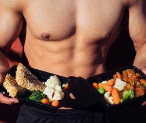 topless man in black shorts holding cooked food