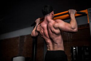 topless man in black shorts doing pull ups