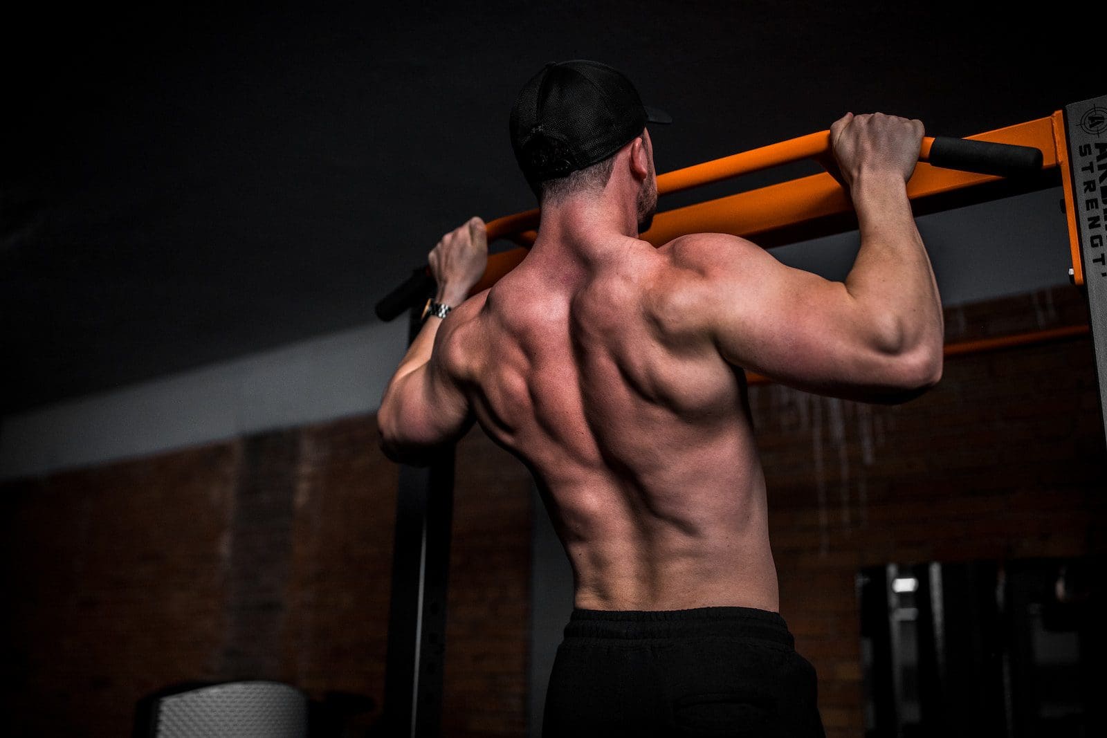 topless man in black shorts doing pull ups